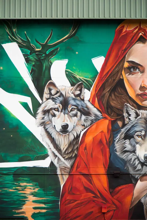 Detalle de mural escolar con ciervo, lobo y Caperucita Roja en fachada de colegio en Madrid