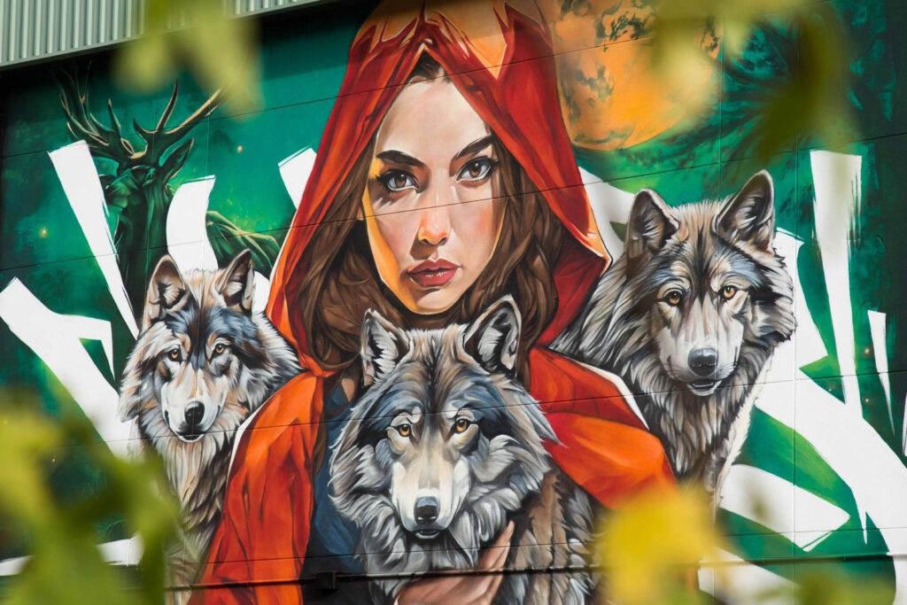 Primer plano del mural de Caperucita Roja con tres lobos en colegio de Madrid