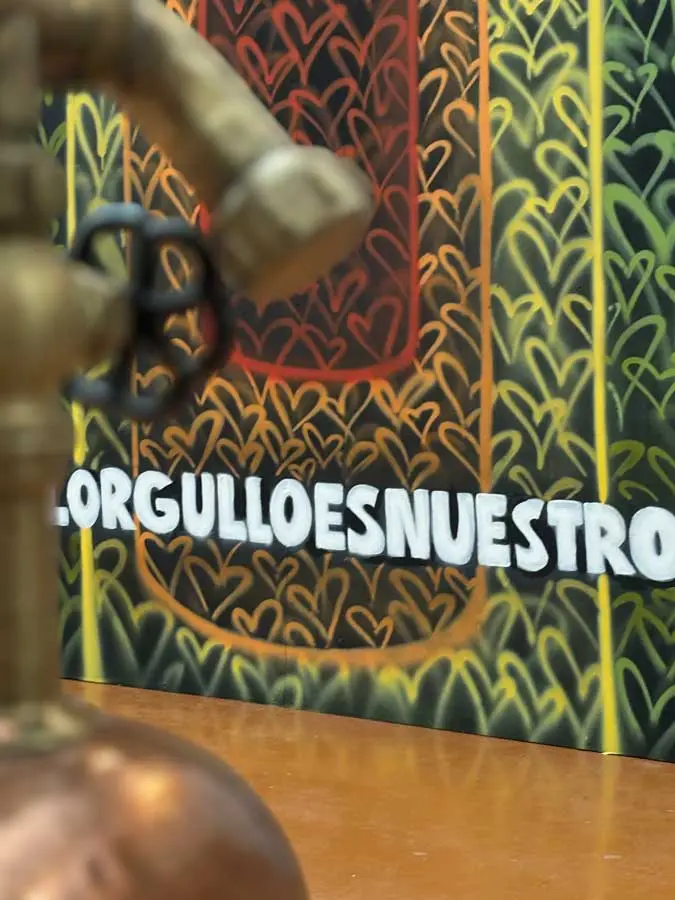 Detalle de mural corporativo LGTBIQ+ con silueta de botella arcoíris y patrón gráfico