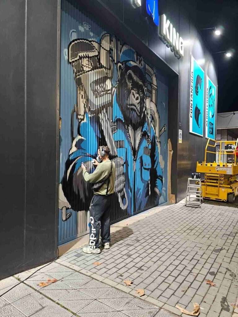 Proceso de mural en puerta industrial de Fontaking con artista pintando el gorila fontanero
