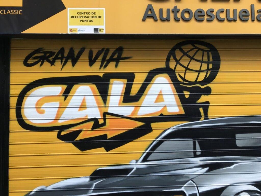 Graffiti de coche deportivo en sede de Autoescuelas Gala en Gran Vía