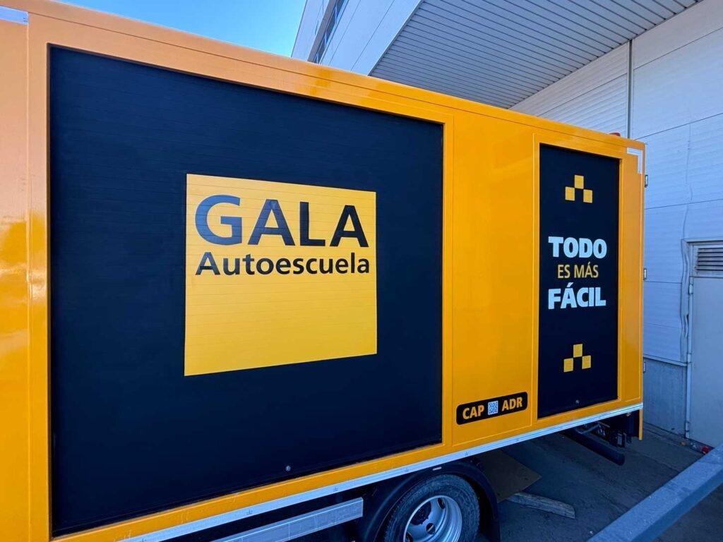 Camión amarillo y negro con rotulación de Autoescuela Gala y lema "Todo es más fácil"
