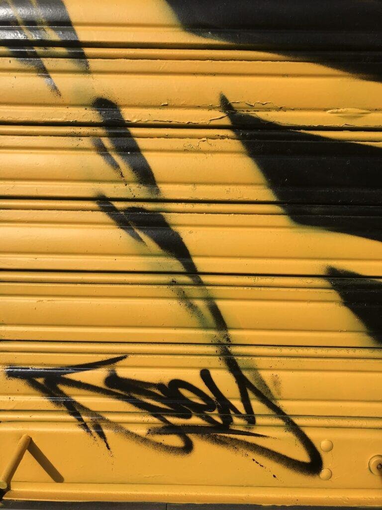 Graffiti BMW negro en persiana de Gala en Paseo de Extremadura