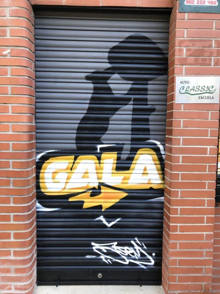 Detalle del logo GALA pintado sobre persiana metálica de GALA Autoescuela Higueras en Madrid