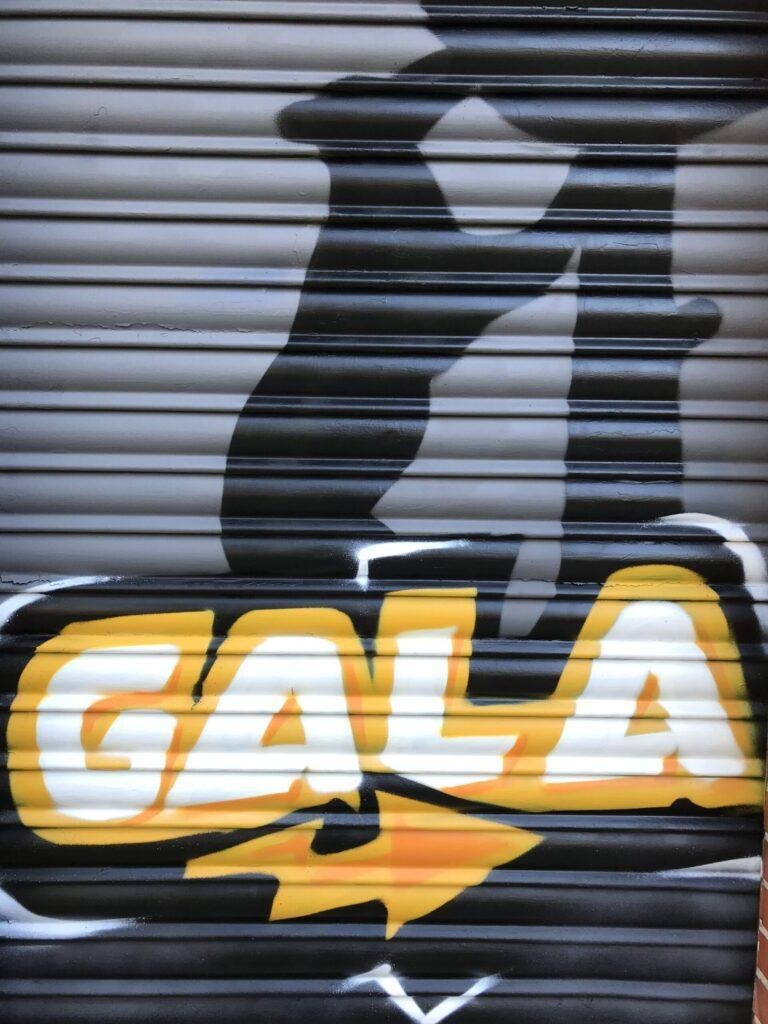 Detalle del logo GALA pintado sobre persiana metálica de GALA Autoescuela Higueras en Madrid