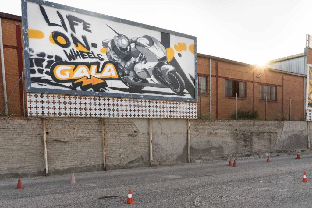 Graffiti con tráiler y texto en vallas publicitarias de Autoescuelas Gala