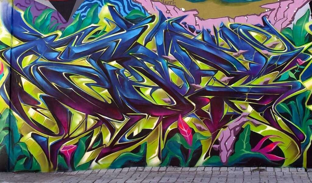 Mural de graffiti con letras en 3D y colores vivos en festival de Brasil