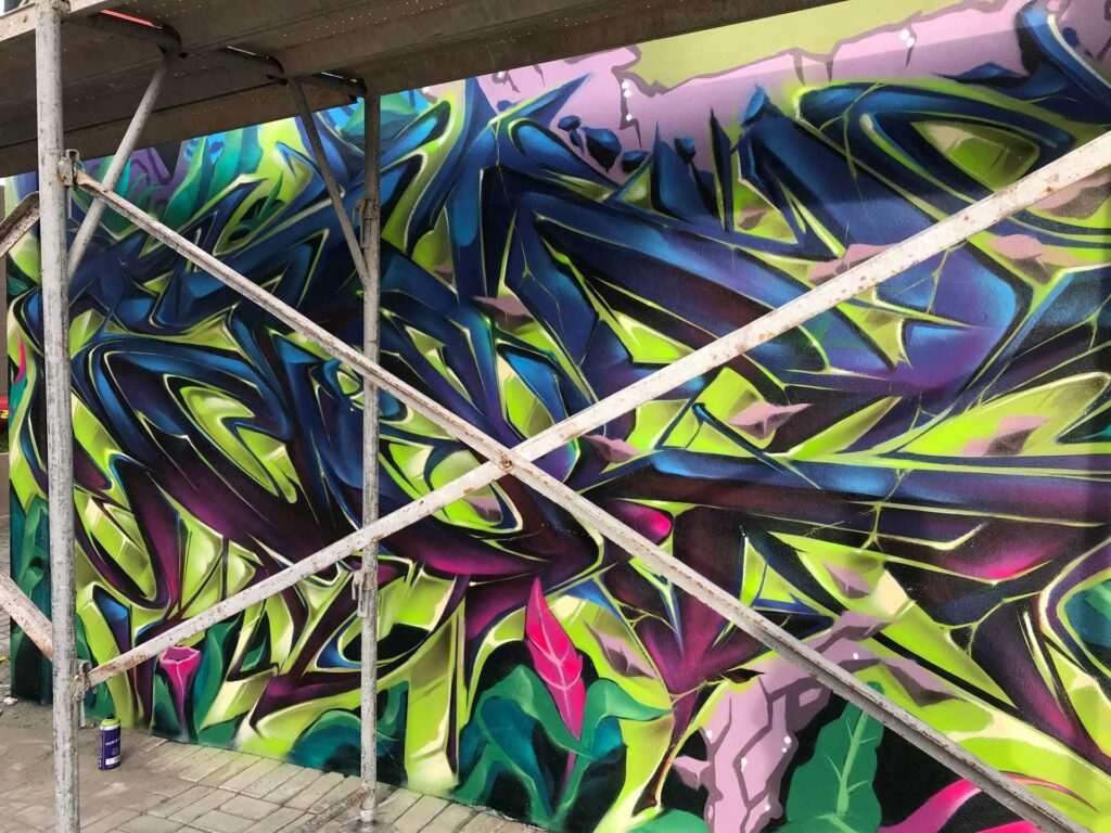 Mural de graffiti con letras en 3D y colores vivos en festival de Brasil