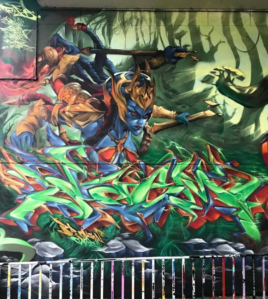 Graffiti de guerrera azul en un bosque con letras wildstyle. Festival Meeting Of Styles en Wiesbaden, Alemania