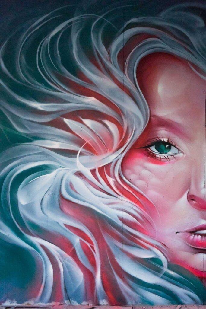 Mural retrato femenino hiperrealista en tonos rosados y blancos