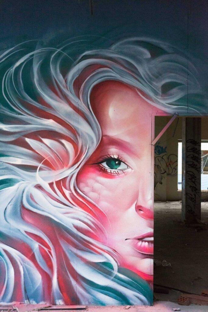 Mural retrato femenino hiperrealista en tonos rosados y blancos