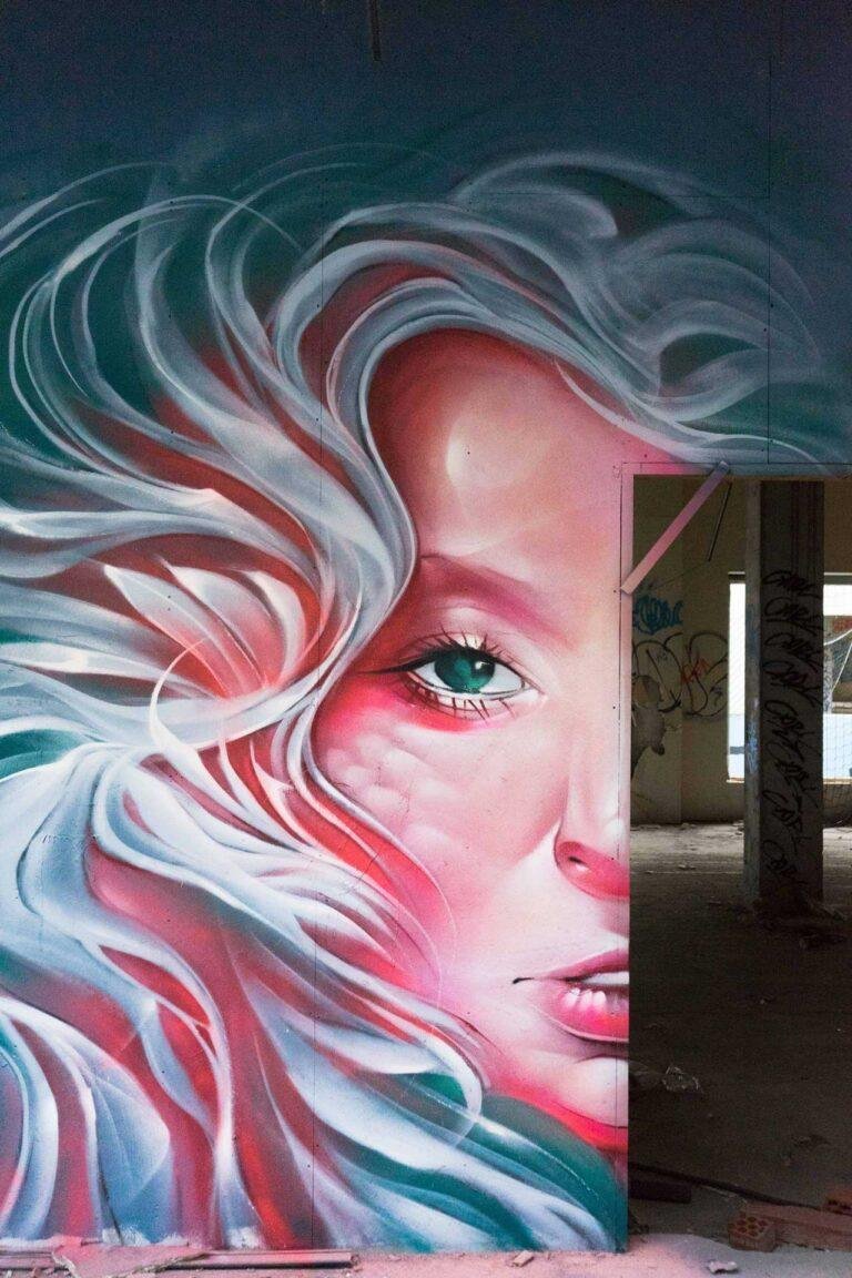 Mural retrato femenino hiperrealista en tonos rosados y blancos