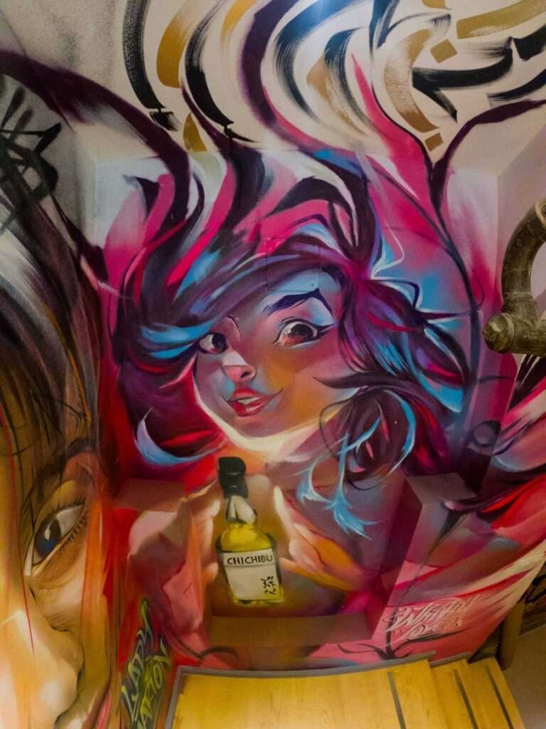 Graffiti interior con retratos y dragón en escalera de acceso a bodega