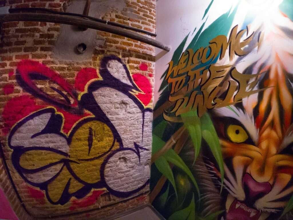 Graffiti interior con retratos y dragón en escalera de acceso a bodega