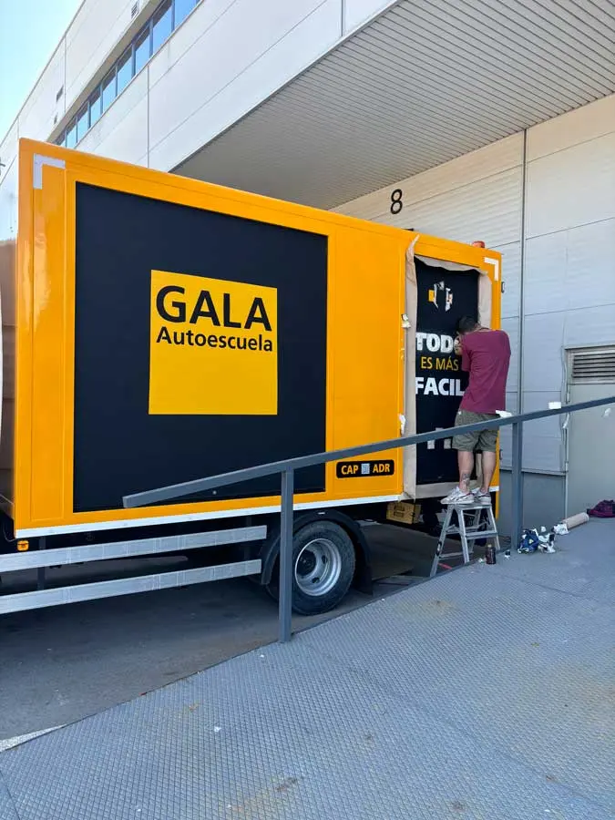 Camión amarillo y negro con rotulación de Autoescuela Gala y lema "Todo es más fácil"