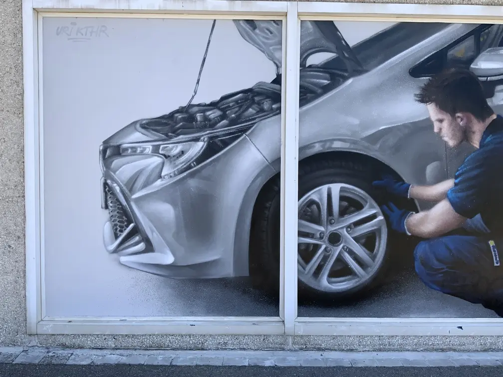 Graffiti profesional con imágenes de coches en taller Euromaster Tortosa