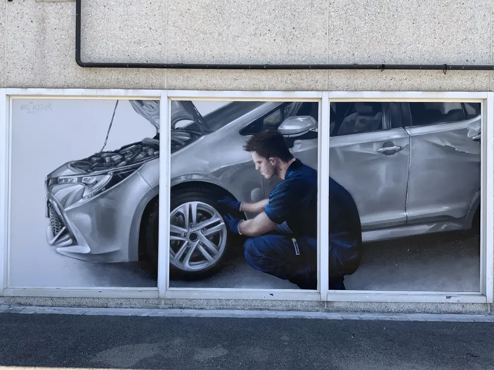 Graffiti profesional con imágenes de coches en taller Euromaster Tortosa