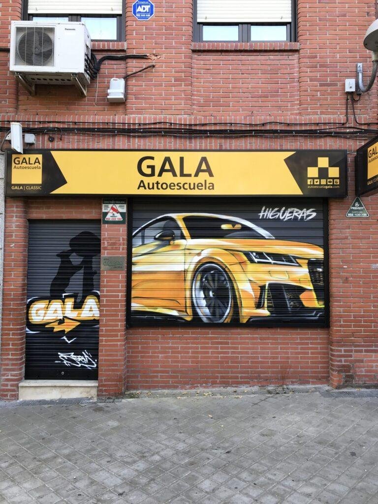 Mural en persiana metálica de GALA Autoescuela Higueras con coche deportivo amarillo y branding corporativo
