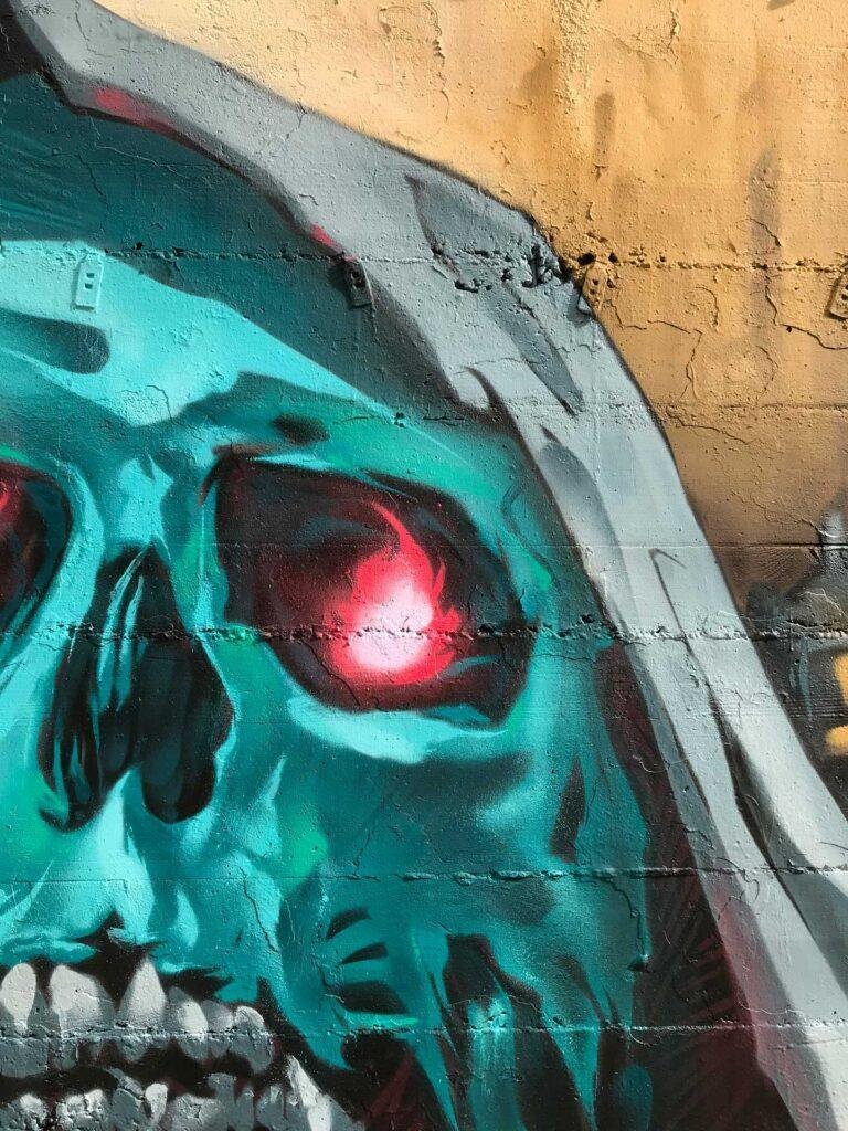 Graffiti de calavera azul con capucha y ojos rojos brillantes