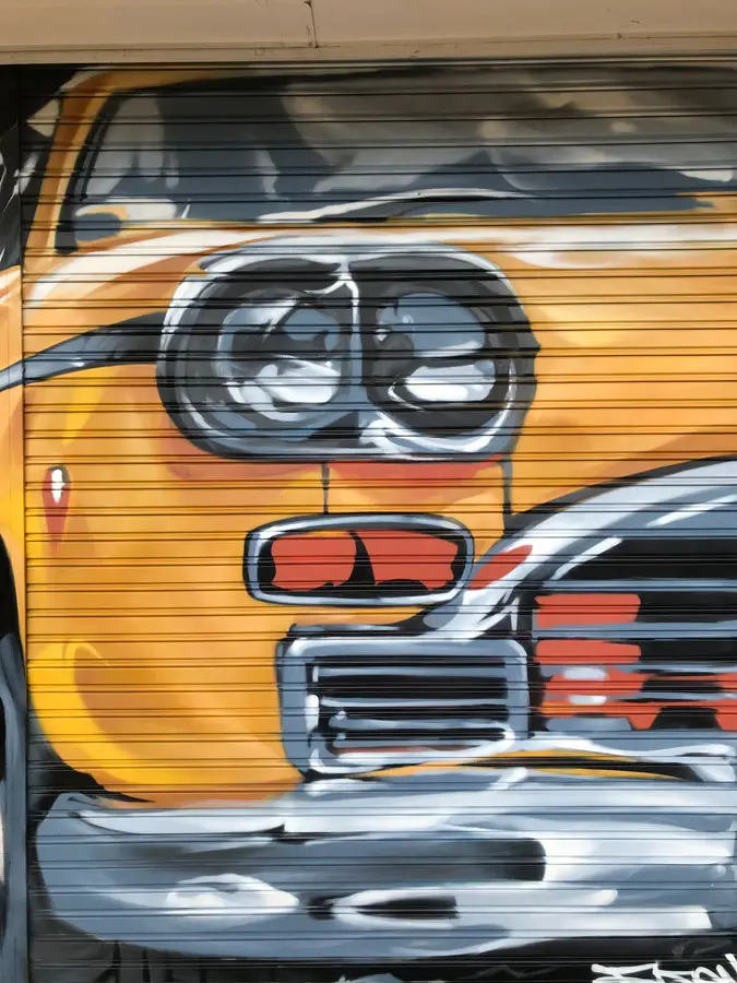 Coche clásico pintado en cierre de Autoescuela Gala Arturo Soria, graffiti realista