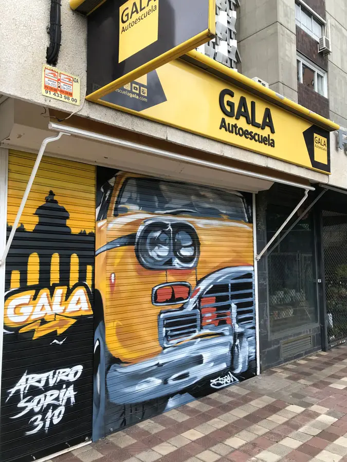 Coche clásico pintado en cierre de Autoescuela Gala Arturo Soria, graffiti realista