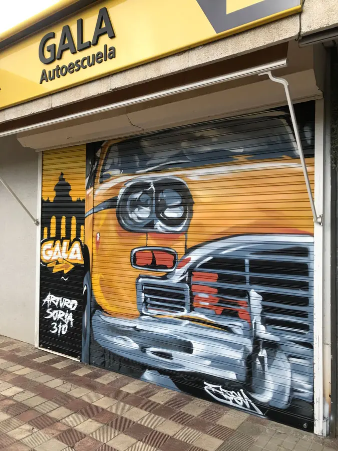 Coche clásico pintado en cierre de Autoescuela Gala Arturo Soria, graffiti realista