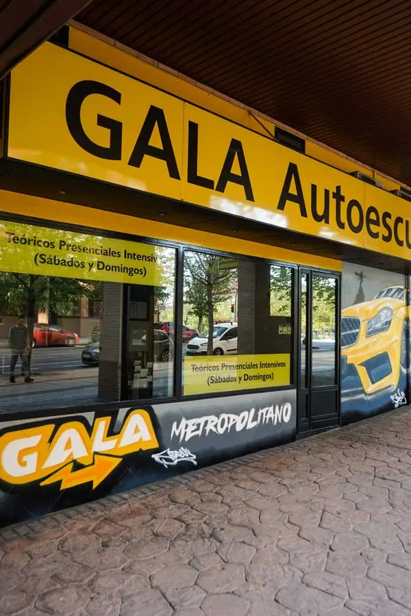 Mural con coche BMW amarillo en fachada de Autoescuela Gala Metropolitano