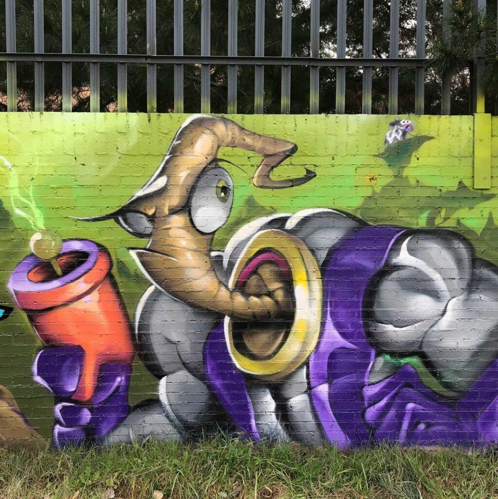 Mural graffiti de Earthworm Jim con raygun sobre fondo verde neón