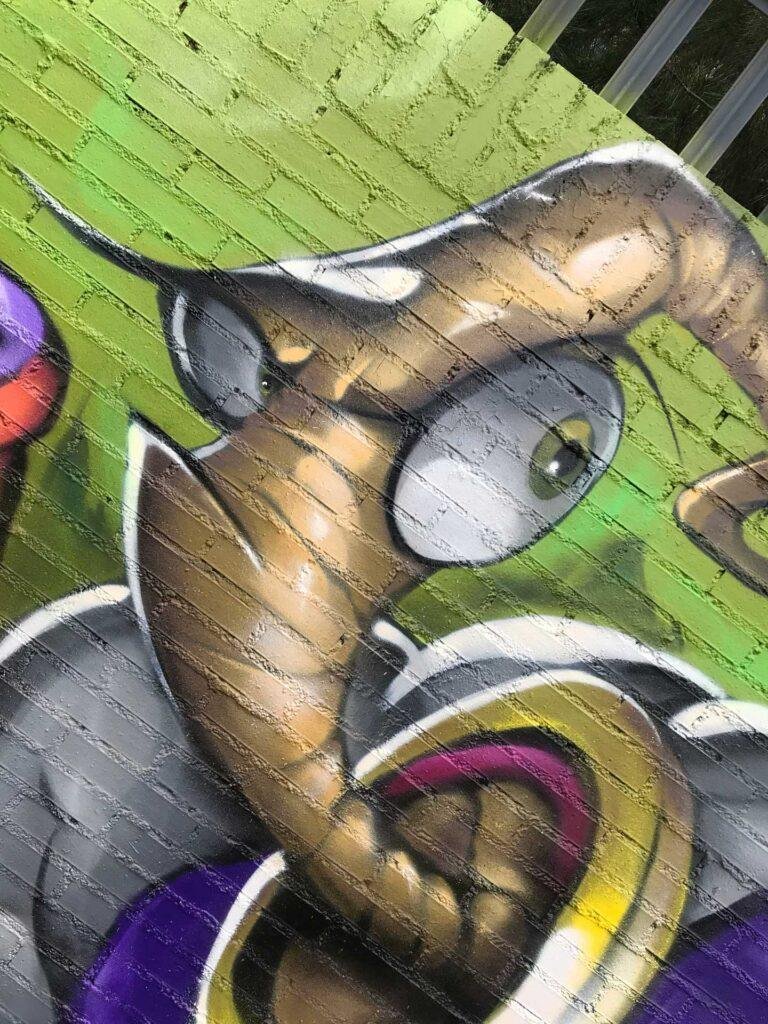 Mural graffiti de Earthworm Jim con raygun sobre fondo verde neón