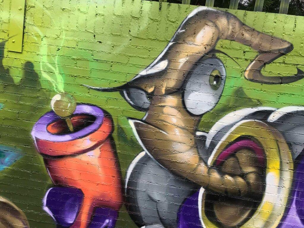 Mural graffiti de Earthworm Jim con raygun sobre fondo verde neón