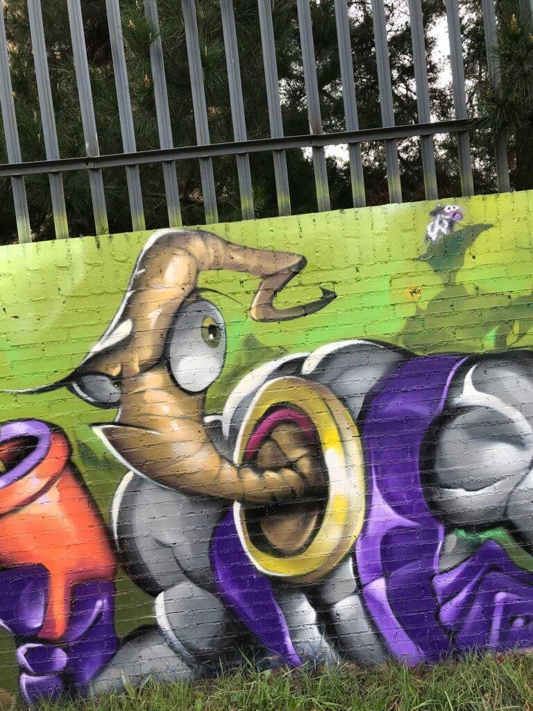 Mural graffiti de Earthworm Jim con raygun sobre fondo verde neón