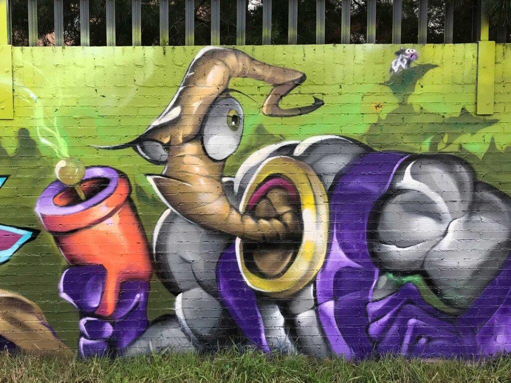 Mural graffiti de Earthworm Jim con raygun sobre fondo verde neón