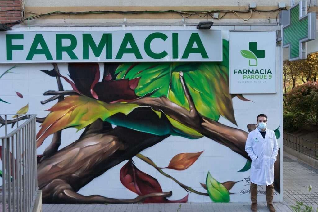 Mural con ramas y hojas en fachada de Farmacia Parque9, graffiti para imagen de salud