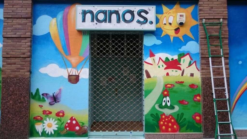 Mural infantil en guardería Nanos con globos, sol, campo y colores alegres