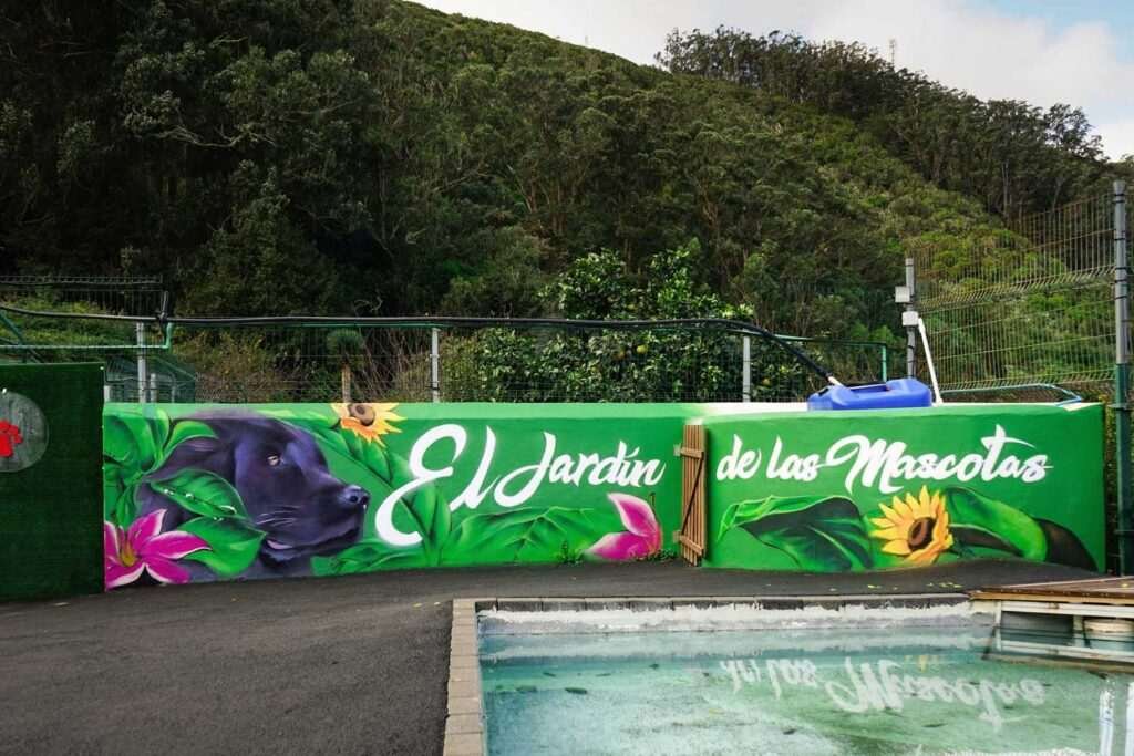 Mural exterior para hotel de mascotas en Tenerife con perro negro y rótulo El Jardín de las Mascotas