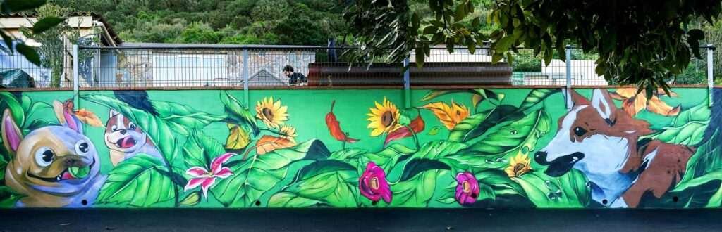 Fragmento del mural con flores, hojas tropicales y colores vivos en el exterior del hotel
