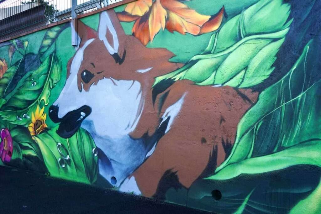 Detalle de mural exterior con zorro entre hojas tropicales para hotel de mascotas en Tenerife