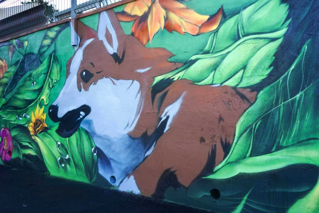 Detalle de mural exterior con zorro entre hojas tropicales para hotel de mascotas en Tenerife