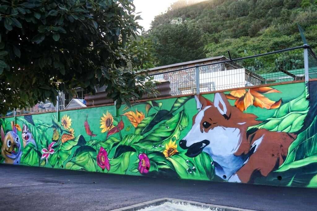 Mural panorámico para hotel de mascotas con vegetación tropical, flores y animales sobre muro exterior