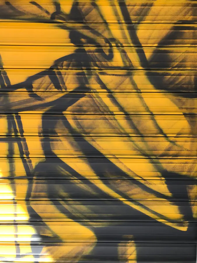 Mural con moto de carreras en cierre metálico del Barrio Blanco (Madrid), estilo urbano