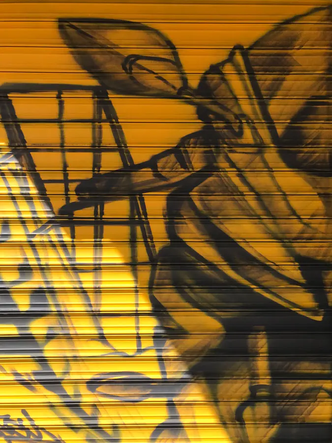Mural con moto de carreras en cierre metálico del Barrio Blanco (Madrid), estilo urbano