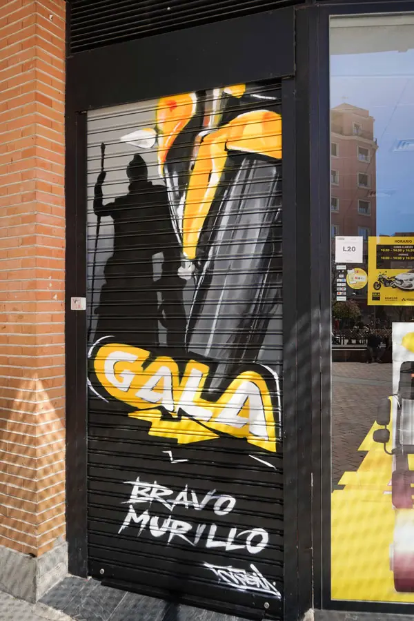 Moto deportiva amarilla y silueta urbana en mural para Gala Bravo Murillo, Madrid