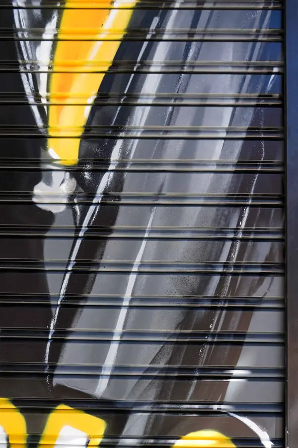 Moto deportiva amarilla y silueta urbana en mural para Gala Bravo Murillo, Madrid