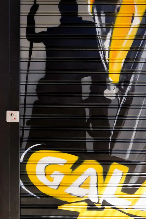 Moto deportiva amarilla y silueta urbana en mural para Gala Bravo Murillo, Madrid