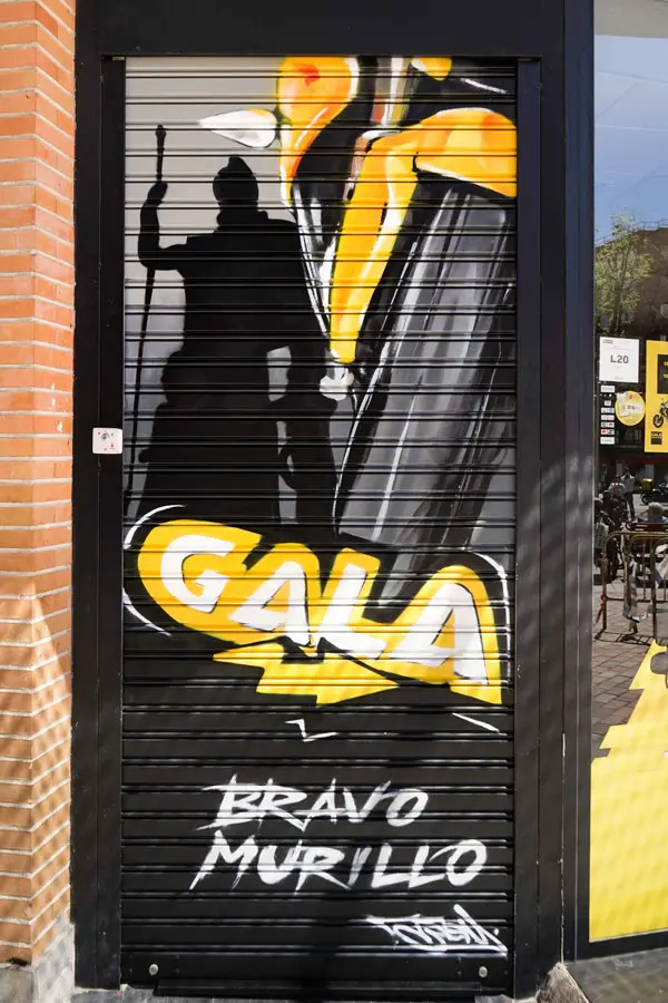 Moto deportiva amarilla y silueta urbana en mural para Gala Bravo Murillo, Madrid