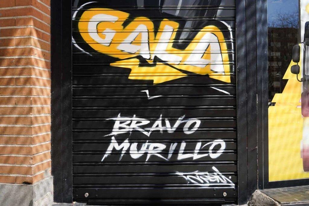 Moto deportiva amarilla y silueta urbana en mural para Gala Bravo Murillo, Madrid