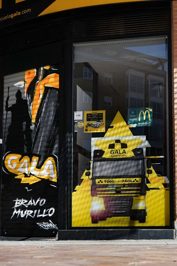 Moto deportiva amarilla y silueta urbana en mural para Gala Bravo Murillo, Madrid