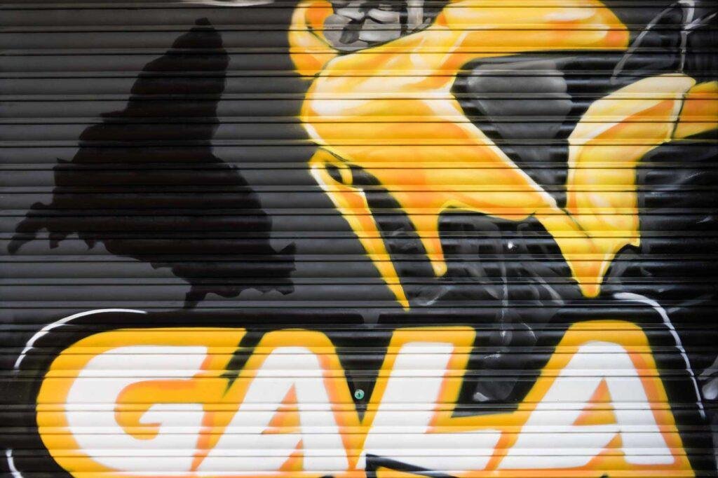 Cierre pintado de Autoescuela Gala con camión y moto en estilo urbano