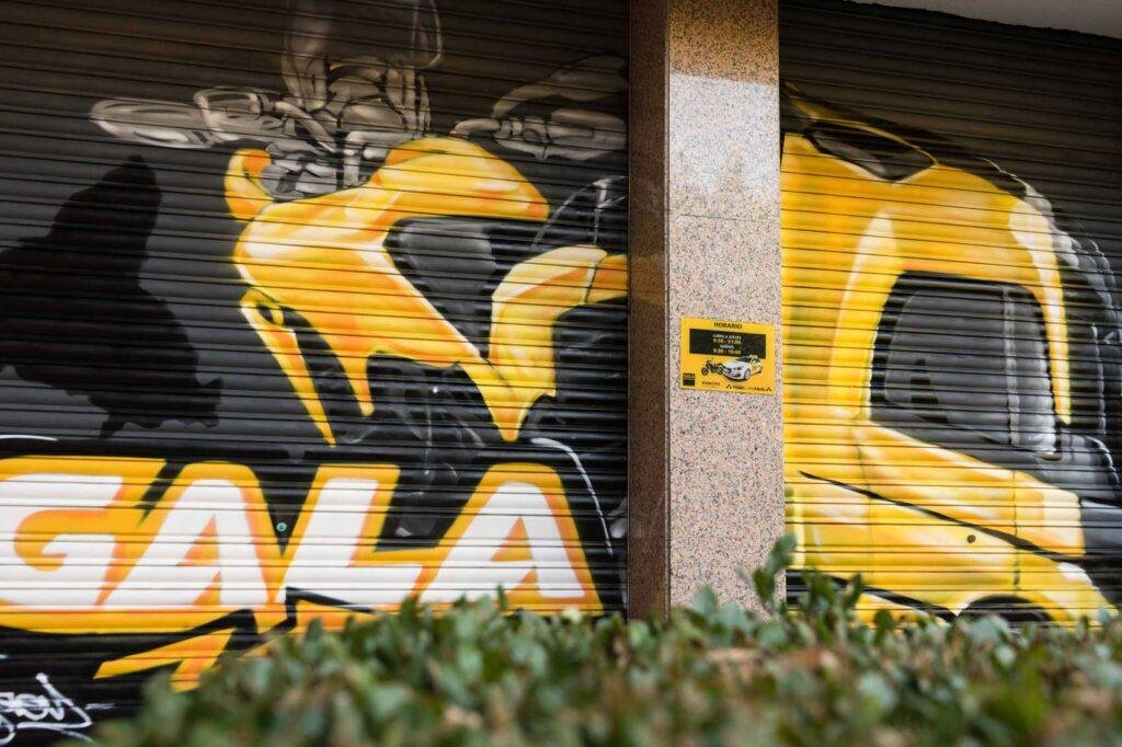 Cierre pintado de Autoescuela Gala con camión y moto en estilo urbano