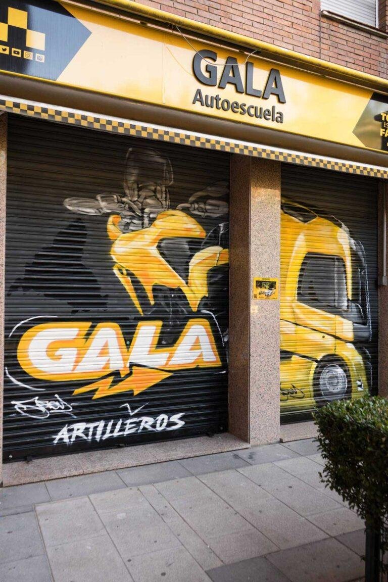 Cierre pintado de Autoescuela Gala con camión y moto en estilo urbano